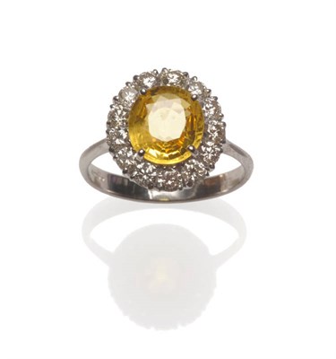 Lot 56 - An 18 Carat White Gold Yellow Sapphire and Diamond Ring, the oval mixed cut sapphire within a...