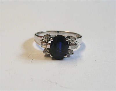 Lot 65 - A Sapphire and Diamond Ring, the oval cut sapphire set between pairs of eight-cut diamonds and...