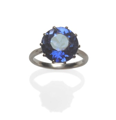 Lot 87 - A Synthetic Sapphire Solitaire Ring, the round brilliant cut sapphire in a white claw setting...