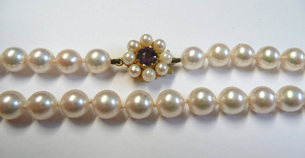 Lot 97 - A Cultured Pearl Necklace, the uniform knotted pearls strung to a 9 carat gold garnet and...