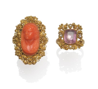 Lot 104 - A Coral Ring, the coral portrait cameo within a filigree floral and scroll frame, on a forked...