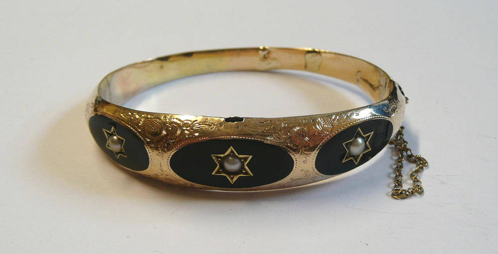 Lot 141 - A Late Victorian Bangle, the bangle front with three graduated oval panels of black enamel each...