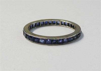 Lot 164 - A Sapphire Full Eternity Ring, the square cut sapphires channel set within a plain white flat sided