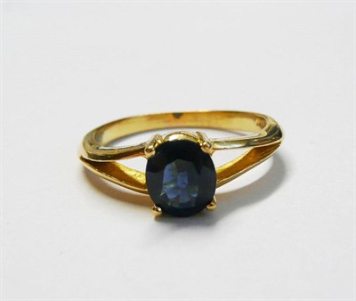 Lot 167 - A Sapphire Solitaire Ring, the oval cut sapphire in a yellow four claw setting, in forked...