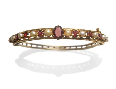 Lot 184 - A 9 Carat Gold Garnet and Cultured Pearl Bangle, an oval cut garnet centrally flanked by...