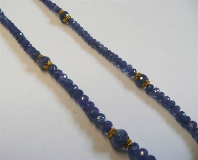 Lot 214 - A Sapphire Necklace, graduated faceted sapphire beads with gold coloured clasps and roundels at...