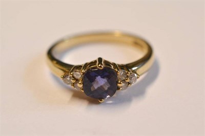 Lot 1034 - A 9 Carat Gold Iolite and Diamond Ring, the cushion shaped faceted iolite flanked by a trio of...