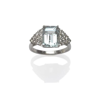 Lot 1092 - An 18 Carat White Gold Aquamarine and Diamond Ring, the step cut aquamarine flanked by a triangular