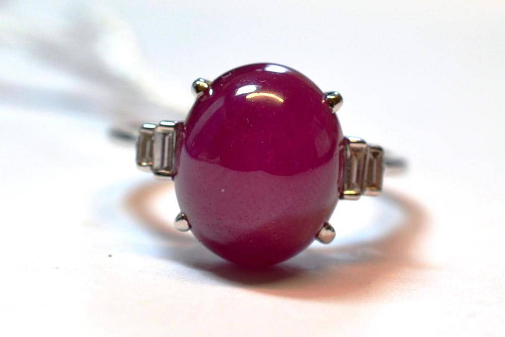 Lot 1099 - A Ruby and Diamond Ring, the cabochon ruby within pairs of graduated baguette cut diamonds on...