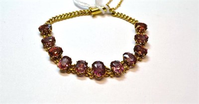 Lot 1142 - A Spinel Bracelet, the graduated pink oval cut stones in yellow claw settings, chain linked, to...