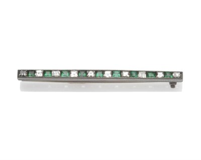 Lot 1188 - An Emerald and Diamond Bar Brooch, the alternating square step cut stones in a white channel...