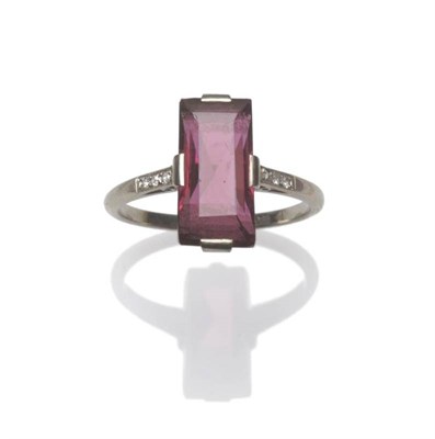 Lot 1238 - A Garnet and Diamond Ring, a scissor cut oblong central garnet in a white four claw setting,...