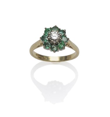 Lot 1091 - An 18 Carat Gold Diamond and Emerald Cluster Ring, a round brilliant cut diamond within a border of