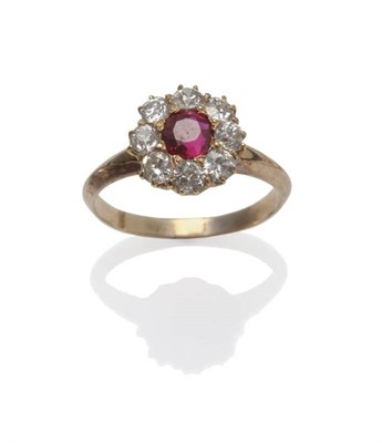 Lot 1047 - A Ruby and Diamond Cluster Ring, the round cut ruby centres a border of eight old cut diamonds,...