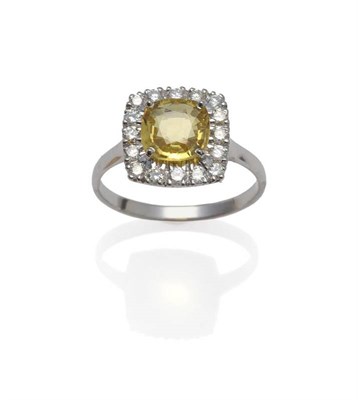 Lot 1061 - An 18 Carat White Gold Yellow Sapphire and Diamond Cluster Ring, the cushion shaped sapphire within