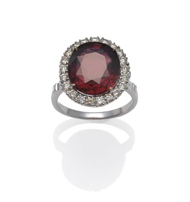 Lot 1072 - An 18 Carat White Gold Garnet and Diamond Cluster Ring, an oval mixed cut garnet within a border of