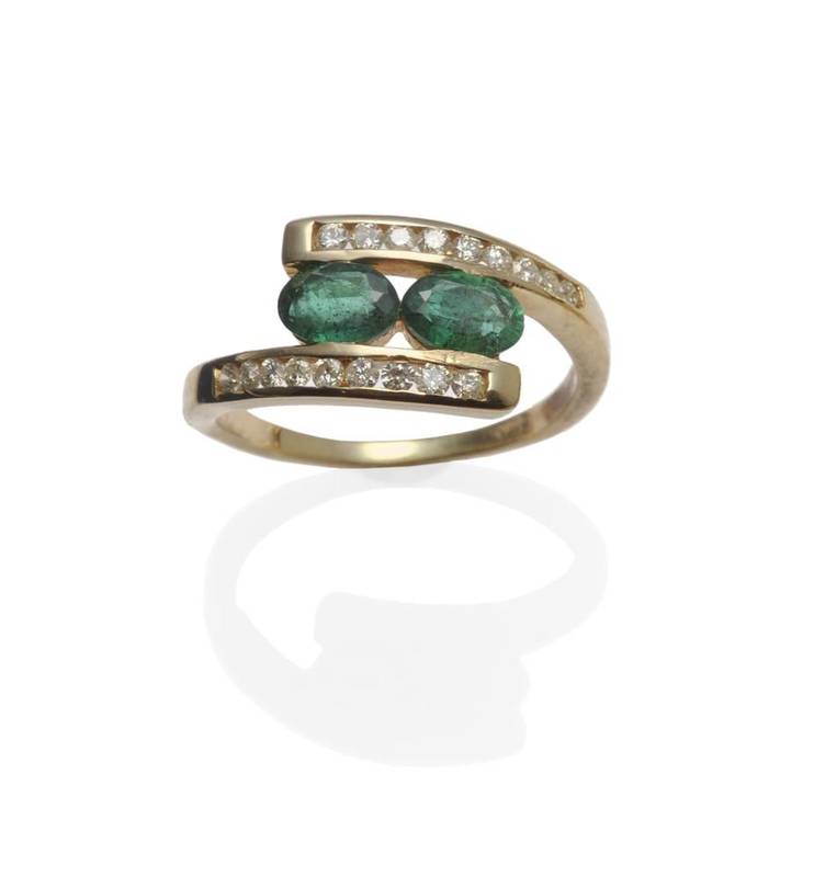 Lot 1083 - An Emerald and Diamond Crossover Ring, two oval cut emeralds tension set between yellow...