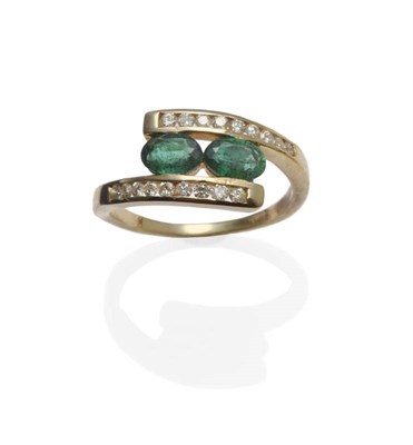 Lot 1083 - An Emerald and Diamond Crossover Ring, two oval cut emeralds tension set between yellow...