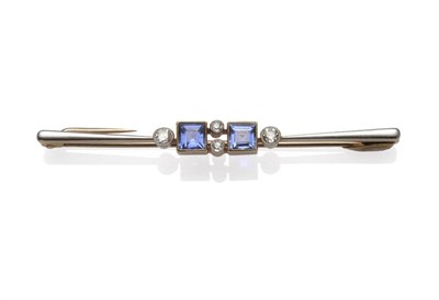 Lot 1119 - An Early 20th Century Bar Brooch, two light blue square step cut sapphires in yellow millegrain...