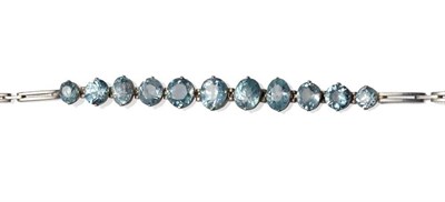 Lot 1152 - A Zircon Bracelet, eleven graduated oval cut blue zircons in white claw settings, to tramline...