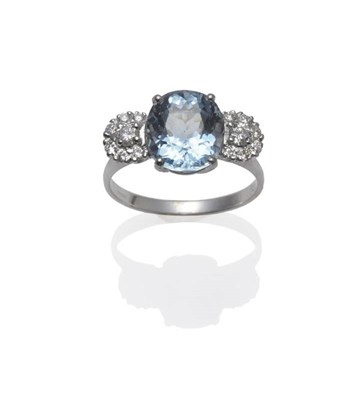 Lot 1155 - An 18 Carat White Gold Aquamarine and Diamond Ring, the oval cut aquamarine between two clusters of