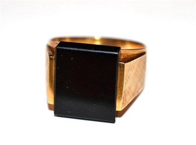 Lot 1162 - An Onyx Ring, circa 1970, the oblong polished onyx within a textured shoulder frame, on a plain...