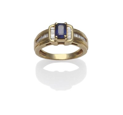 Lot 1171 - A Sapphire and Diamond Ring, the emerald-cut sapphire within a yellow four claw setting, with...