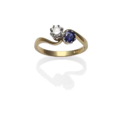 Lot 1173 - An 18 Carat Gold Sapphire and Diamond Two Stone Crossover Ring, the round mixed cut sapphire...