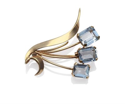 Lot 1178 - An Aquamarine Brooch, in spray form and set with three emerald-cut aquamarines, in yellow claw...