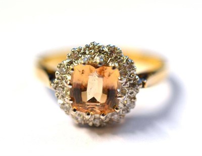 Lot 1204 - An 18 Carat Gold Topaz and Diamond Cluster Ring, the mixed cut topaz within a border of round...