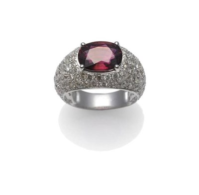 Lot 1239 - A Pink Tourmaline and Diamond Cluster Ring, the oval mixed cut pink tourmaline in white claw...