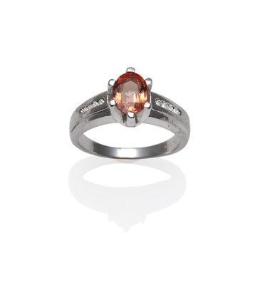 Lot 1154 - An 18 Carat White Gold Padparadscha and Diamond Ring, the oval mixed cut padparadscha sapphire in a