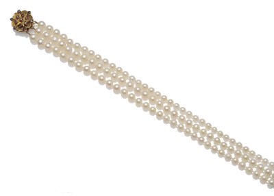 Lot 1179 - A Three Row Cultured Pearl Choker, the graduated pearls knotted to a 9ct gold garnet set clasp,...