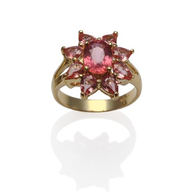 Lot 1186 - An 18 Carat Gold Padparadscha Cluster Ring, the central oval mixed cut padparadscha sapphire within