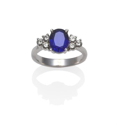 Lot 1217 - A Synthetic Sapphire and Diamond Ring, the oval cut synthetic sapphire flanked by a trio of...