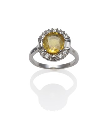 Lot 1223 - An 18 Carat White Gold Yellow Sapphire and Diamond Ring, an oval mixed cut yellow sapphire in a...