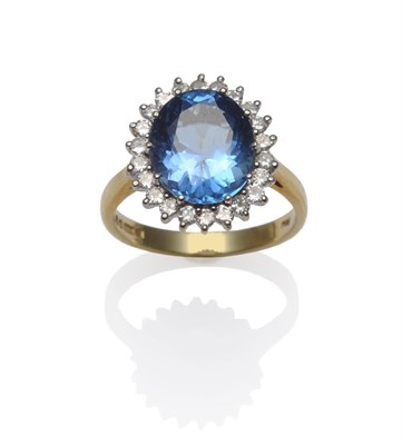 Lot 1250 - An 18 Carat Gold Blue Topaz and Diamond Cluster Ring, the oval cut blue topaz within a border...