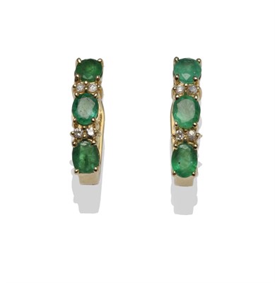 Lot 1256 - A Pair of Emerald and Diamond Earrings, each with three oval cut emeralds, spaced with pairs of...