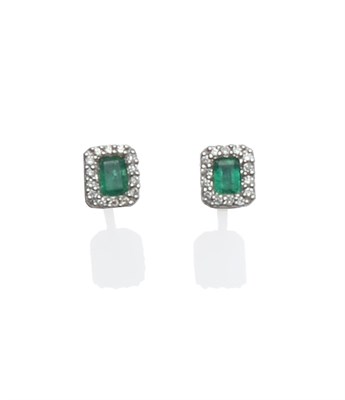Lot 2033 - A Pair of 18 Carat White Gold Emerald and Diamond Cluster Earrings, the emerald-cut emerald...