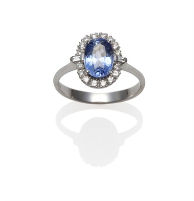 Lot 2121 - An 18 Carat White Gold Sapphire and Diamond Cluster Ring, an oval mixed cut sapphire within a...