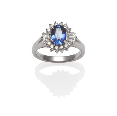 Lot 2039 - An 18 Carat White Gold Sapphire and Diamond Cluster Ring, the oval mixed cut sapphire within a...