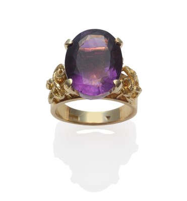 Lot 2051 - An Amethyst Ring, an oval mixed cut amethyst in a yellow claw setting, to textured scrolling...
