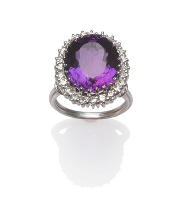 Lot 2069 - An Amethyst and Diamond Cluster Ring, an oval cut amethyst within a border of round brilliant...