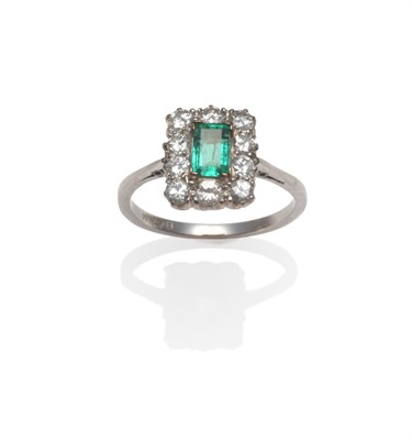 Lot 2083 - An Emerald and Diamond Cluster Ring, the emerald-cut emerald within a border of round brilliant cut