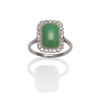 Lot 2112 - A Jade and Diamond Cluster Ring, an oblong cabochon jade within a border of eight-cut diamonds,...