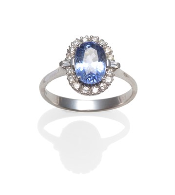 Lot 2138 - An 18 Carat White Gold Sapphire and Diamond Cluster Ring, an oval mixed cut sapphire within a...