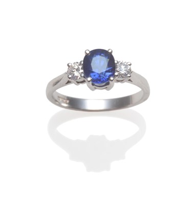 Lot 2139 - An 18 Carat White Gold Sapphire and Diamond Ring, an oval cut sapphire between two round...