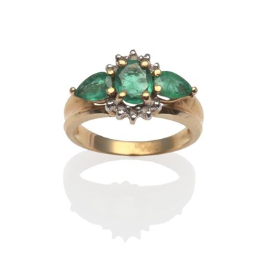 Lot 2068 - An Emerald and Diamond Ring, an oval cut emerald flanked by pear cut emeralds and round...