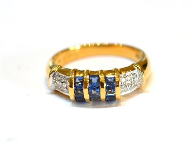 Lot 2130 - A Sapphire and Diamond Ring, set with calibré cut sapphires on a three row yellow channel setting