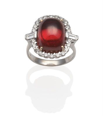 Lot 2024 - An 18 Carat White Gold Garnet and Diamond Cluster Ring, an oval cabochon garnet within a border...